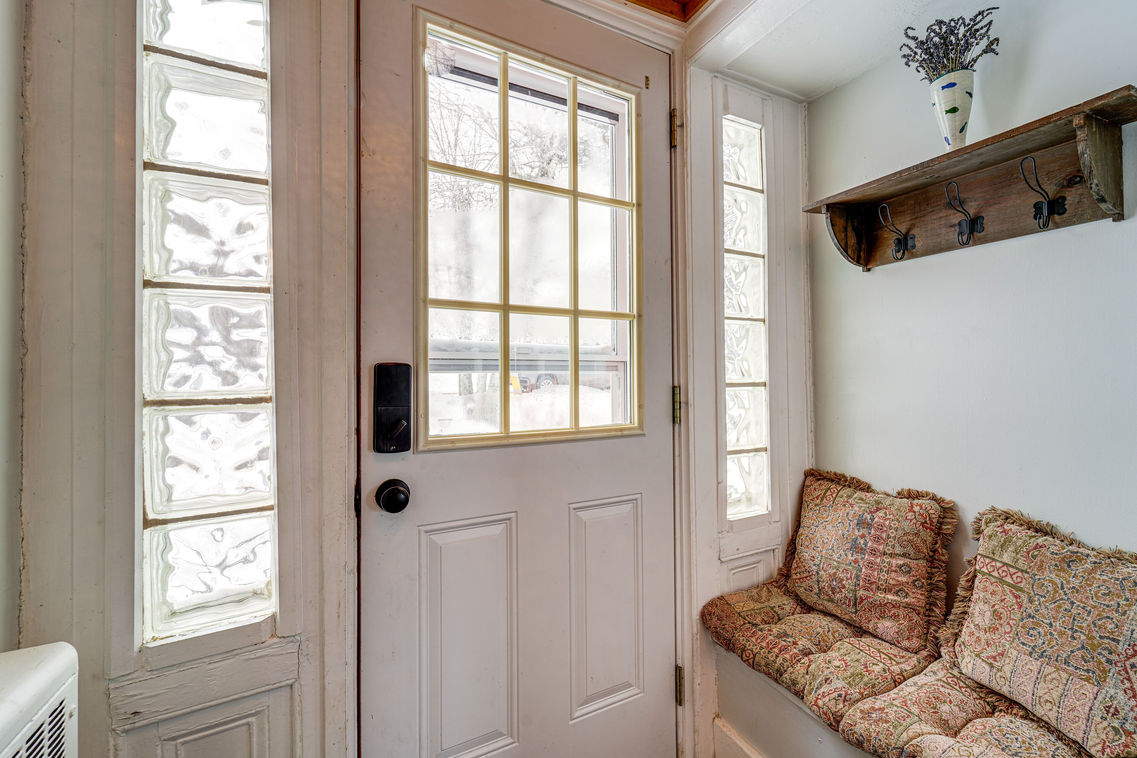 A white door with frosted glass panels and a bench with patterned cushions.