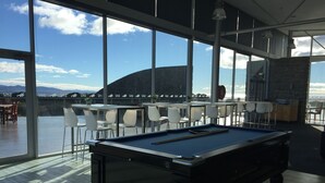 Una mesa de billar en una habitación con ventanales amplios que dan a una vista panorámica.