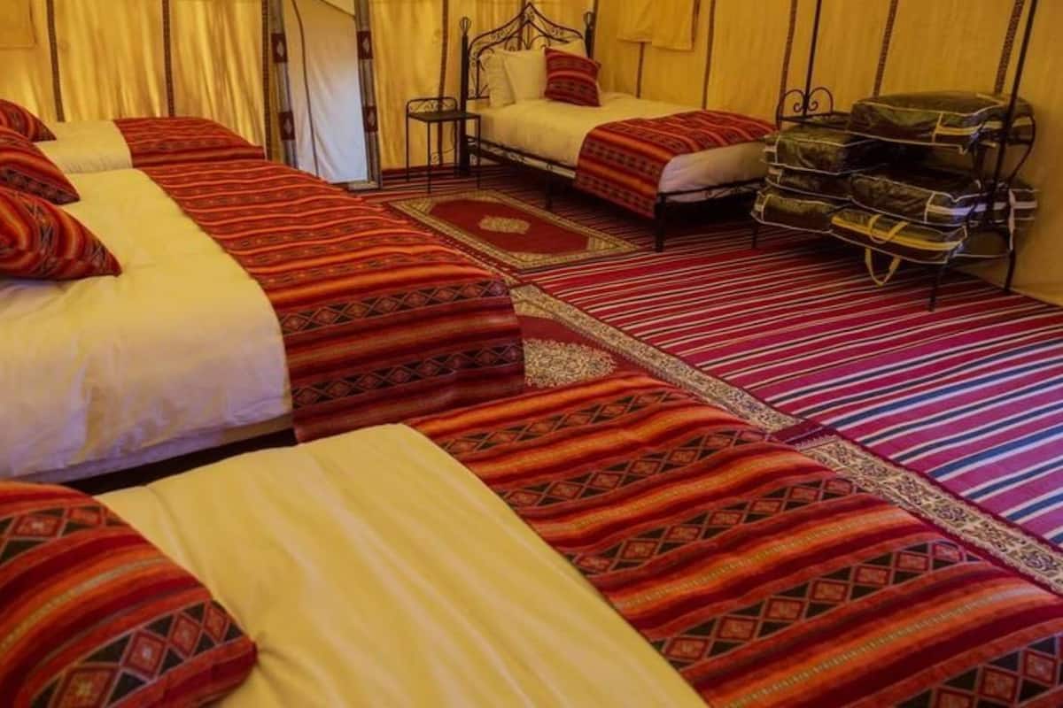 Une chambre d’hôtel avec deux lits, chacun agrémenté de draps rouges et blancs, une petite table et une chaise.