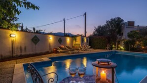 Uma área de piscina com espreguiçadeiras e uma mesa com copos e uma vela.