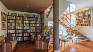 Uma biblioteca ampla com várias estantes, uma escadaria e áreas de estar confortáveis.