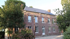 A two-story brick building with a symmetrical facade, multiple windows, and a gravel driveway. - Authentic Norman house between countryside and sea (Lindebeuf)