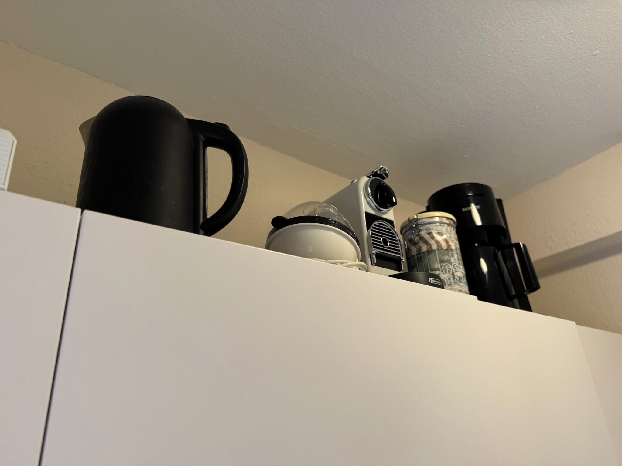 Ein Küchenbereich mit einer Kaffeemaschine, einem Wasserkocher und einem Thermos auf der Arbeitsfläche.