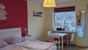 Una camera da letto con un letto, una scrivania, una sedia e una finestra vista edifici.