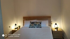 A bedroom with a wooden headboard, a bed with white bedding, a zebra-patterned pillow, bedside lamps, and a wall-mounted light fixture. - Il Silenzio   ground floor (Magarikari)