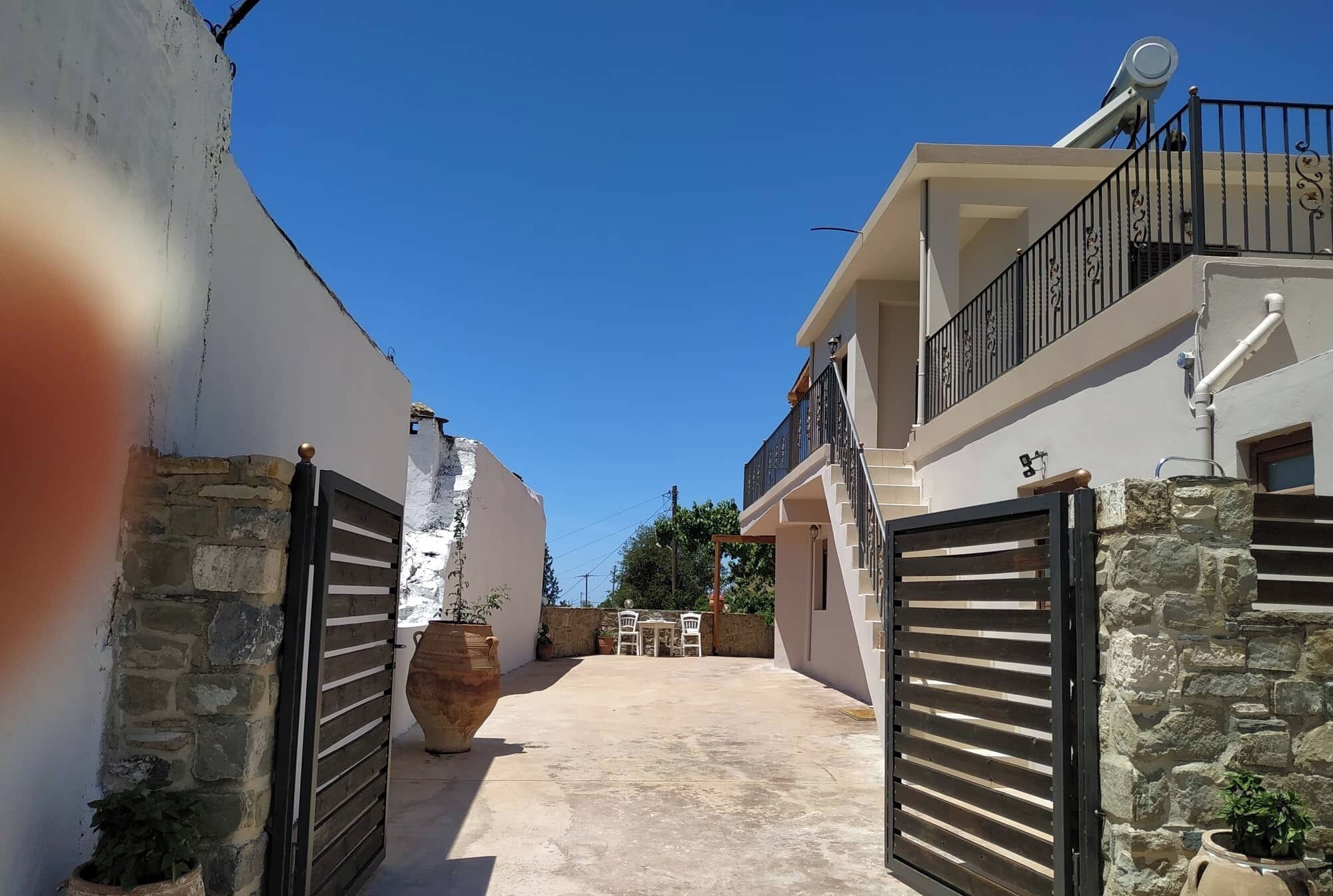 A residential building with a gated entrance, a balcony, and a patio area with outdoor furniture.