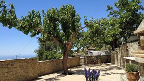 A stone-walled courtyard with a table and chairs, surrounded by trees and potted plants. - Il Silenzio   ground floor (Magarikari)