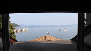 A view from a window overlooking a calm body of water with boats and a dock.