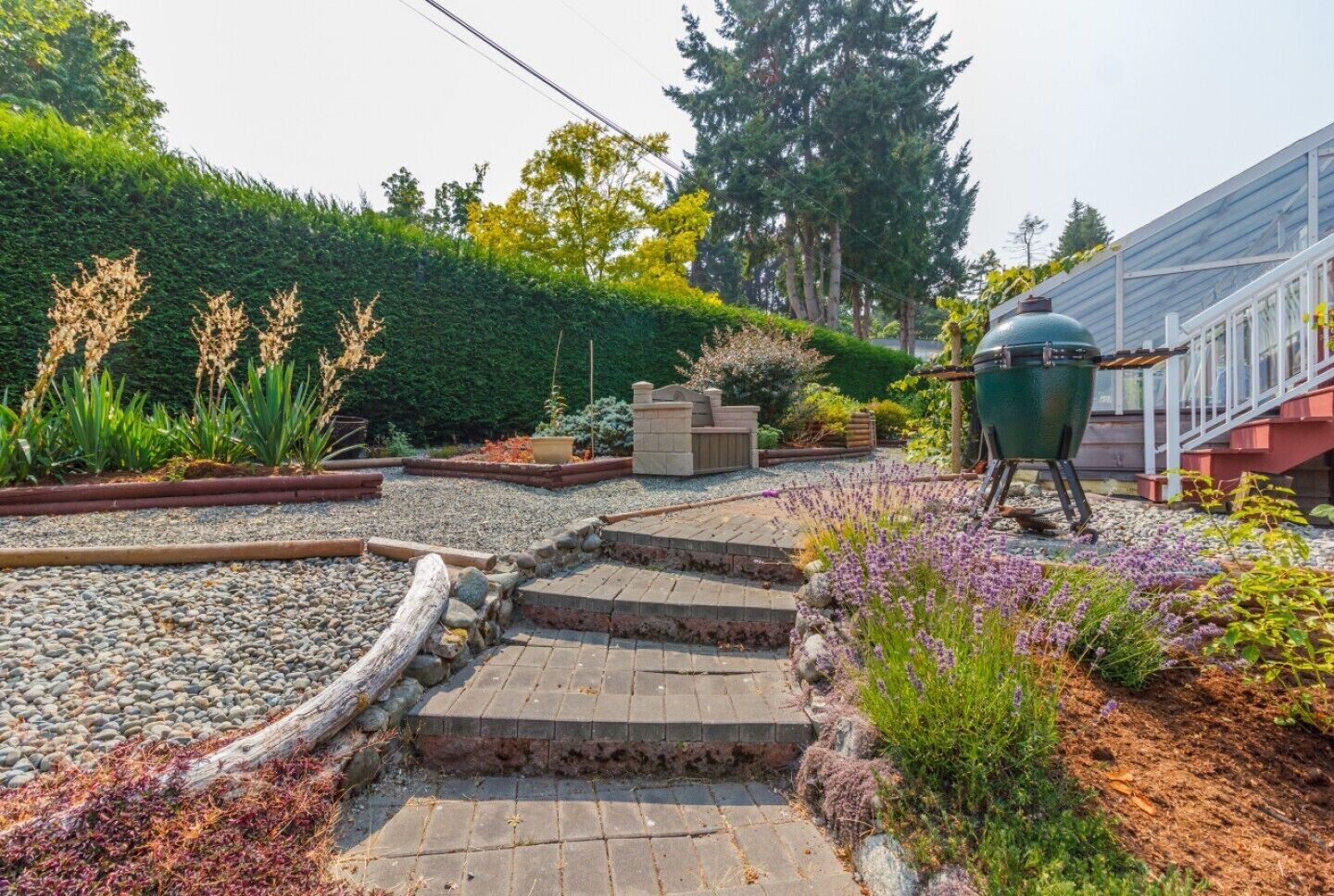 A garden with a barbecue grill, stone steps, and various plants.