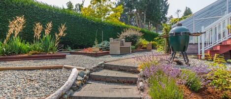 A garden with a barbecue grill, stone steps, and various plants.