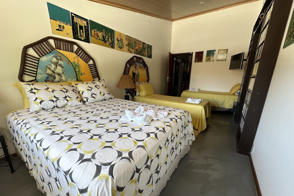 A hotel room with a large bed, two smaller beds, and a wall decorated with framed pictures.