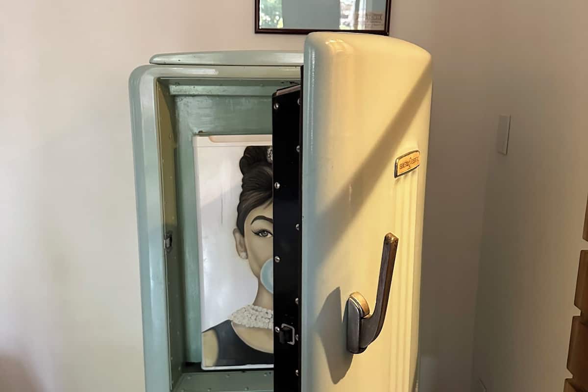 A vintage refrigerator with a picture of a woman on the door.