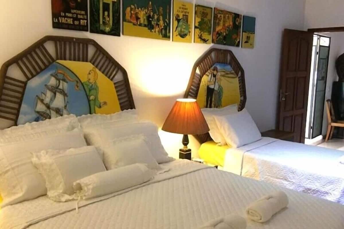 A hotel room with two beds, a lamp, and wall art.