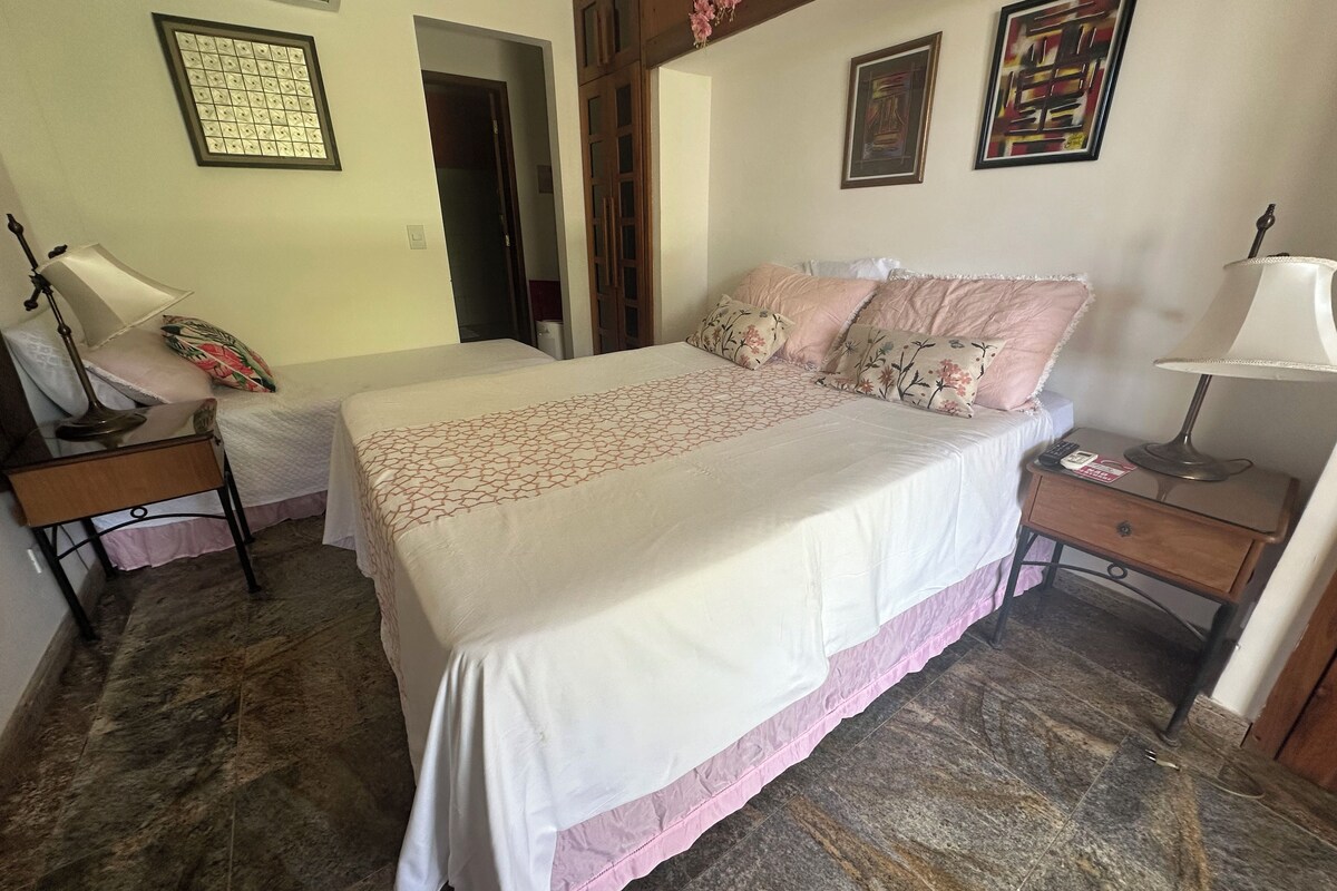 A bedroom with a bed, bedside tables, a lamp, and a wall-mounted light fixture.