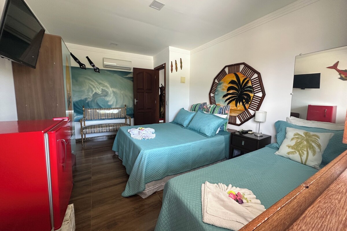 A hotel room with two beds, a red dresser, a TV, and a mural on the wall.