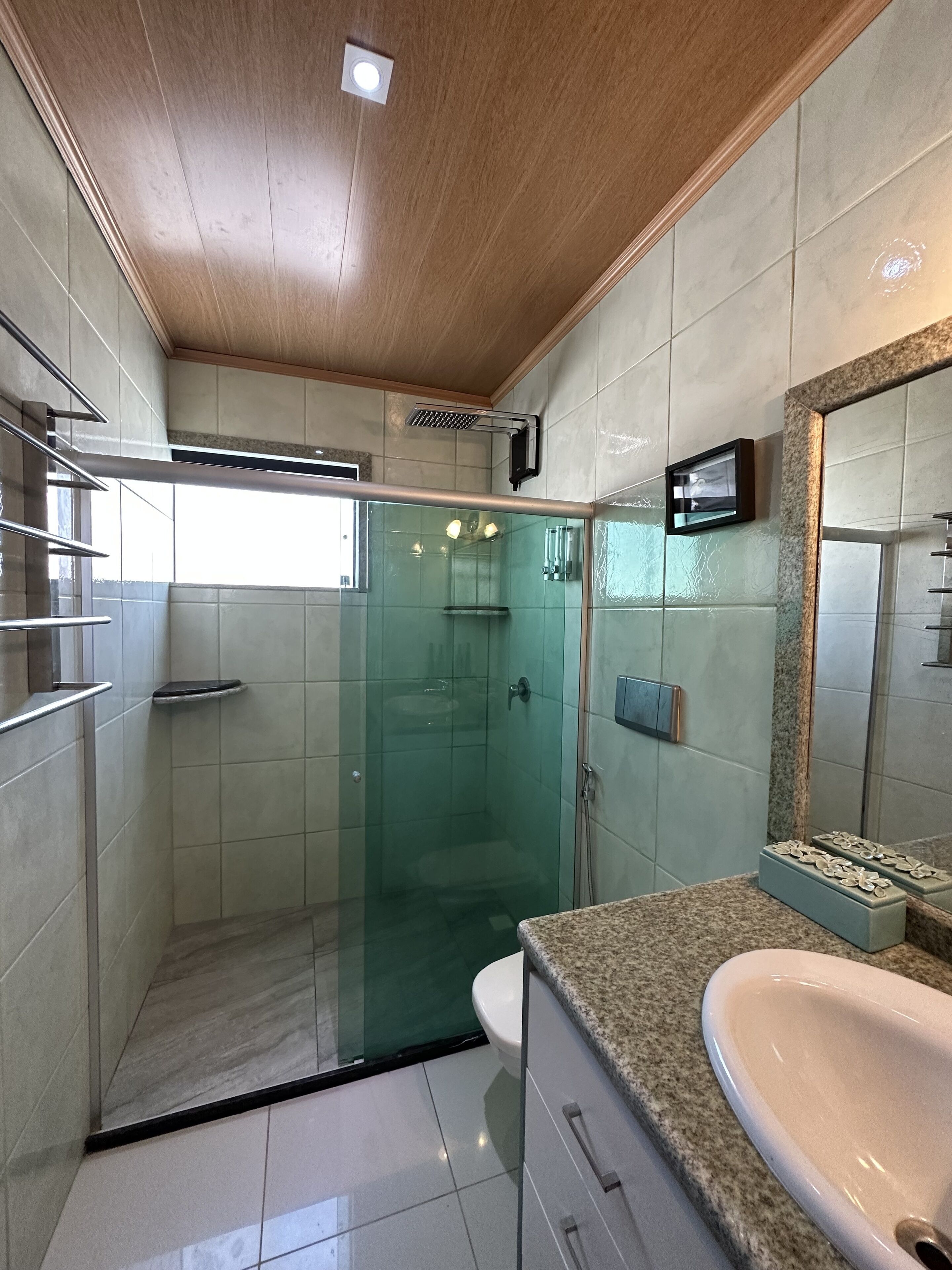 A modern bathroom with a glass-enclosed shower, a vanity with a sink, and a mirror.