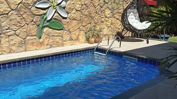 A swimming pool with a stone wall and a large flower mural.