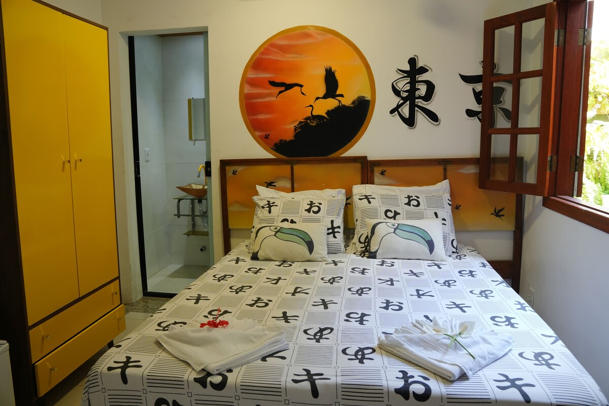 A hotel room with a bed featuring a patterned bedspread, a wall with a circular artwork, and a wooden wardrobe.