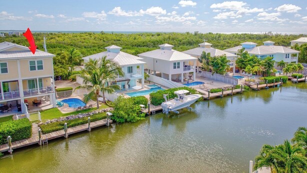 A waterfront property with multiple houses, a swimming pool, and a dock with a boat. - W04 - Spacious 4 bed, 3 bath home in Sombrero with private pool (Marathon)