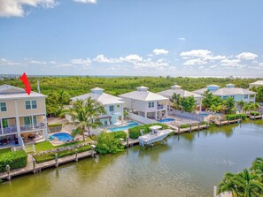 Une propriété située au bord de l’eau, comprenant plusieurs maisons, une piscine et un quai avec un bateau.