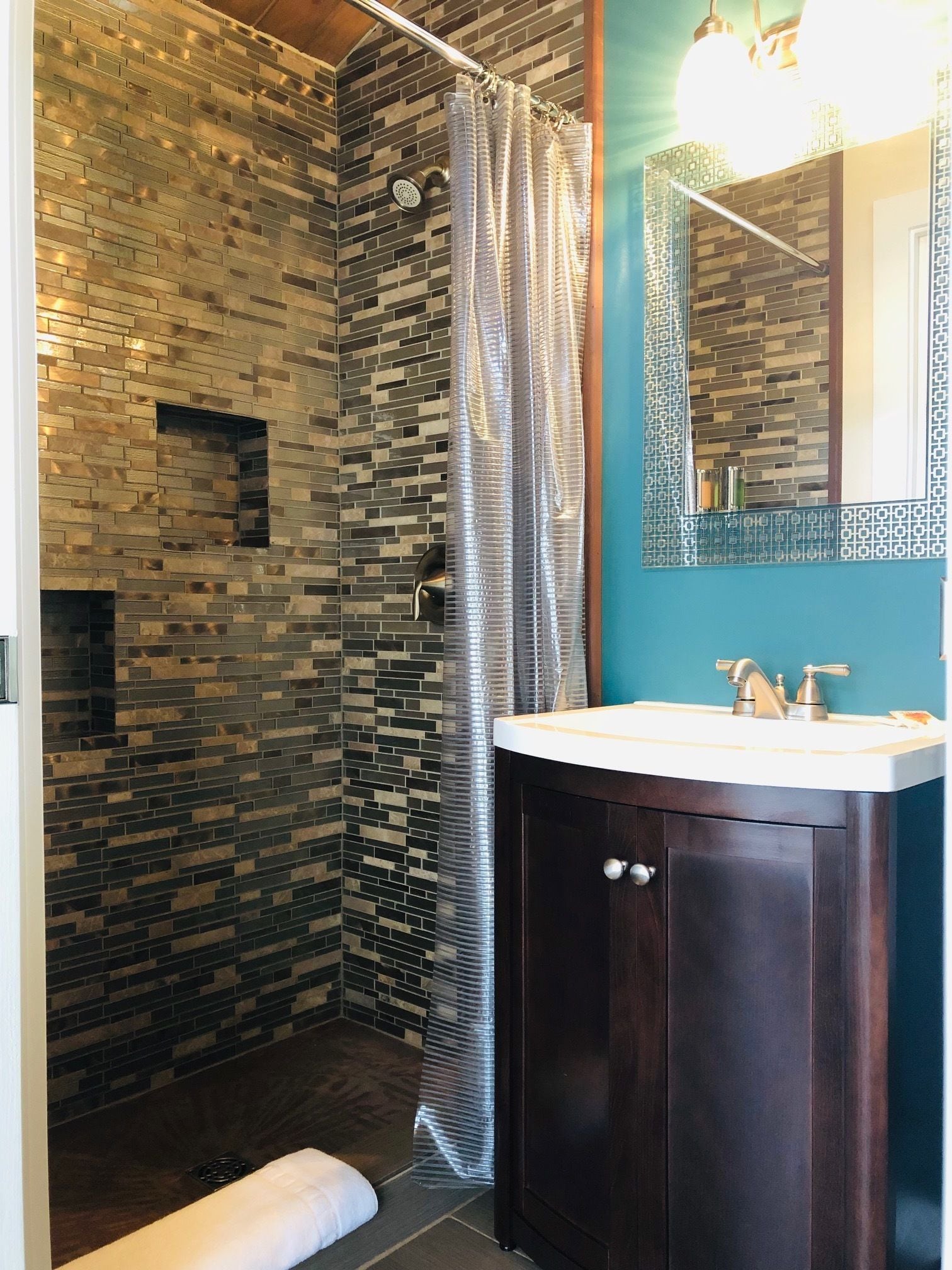 A modern bathroom with a shower, a sink, and a mirror.