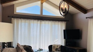 Un dormitorio con una cama grande, televisión, escritorio y ventana con cortinas.