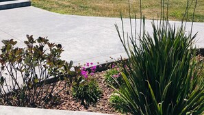 Un jardín ajardinado con un camino de hormigón, diversas plantas y vistas al océano.
