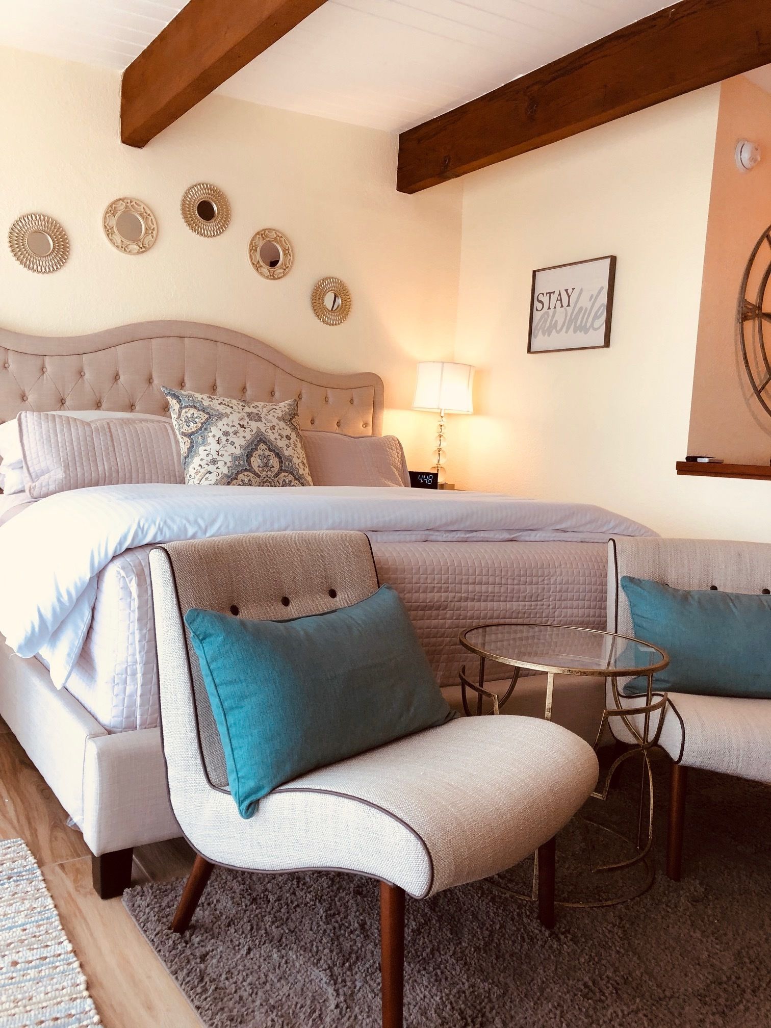 A bedroom with a large bed, a bedside table, a chair, and a small round table.