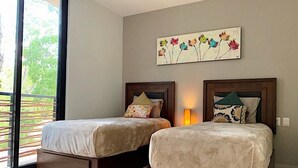 Quarto com duas camas, uma janela grande e um quadro na parede.