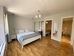 A bedroom with a bed, bedside tables, a mirror, a hanging light fixture, and a wooden floor. - Mon Petit Hotel (Bozcaada)