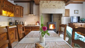 A cozy kitchen with wooden cabinets, a stove, and a dining table set with placemats and a vase with flowers.