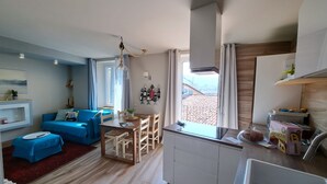 Un espai habitable compacte amb cuineta, zona de dinar i saló amb un sofà blau i una taula petita.