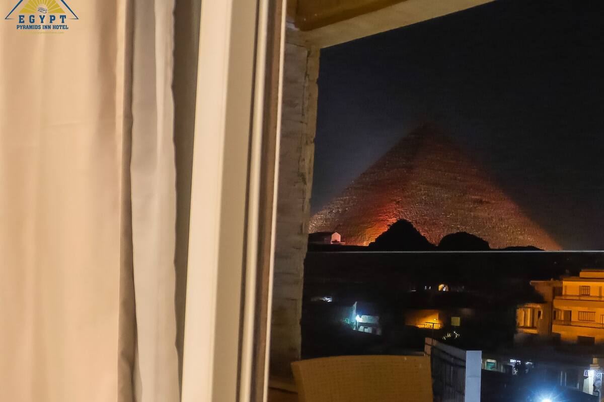 A hotel room with a view of a pyramid at night.
