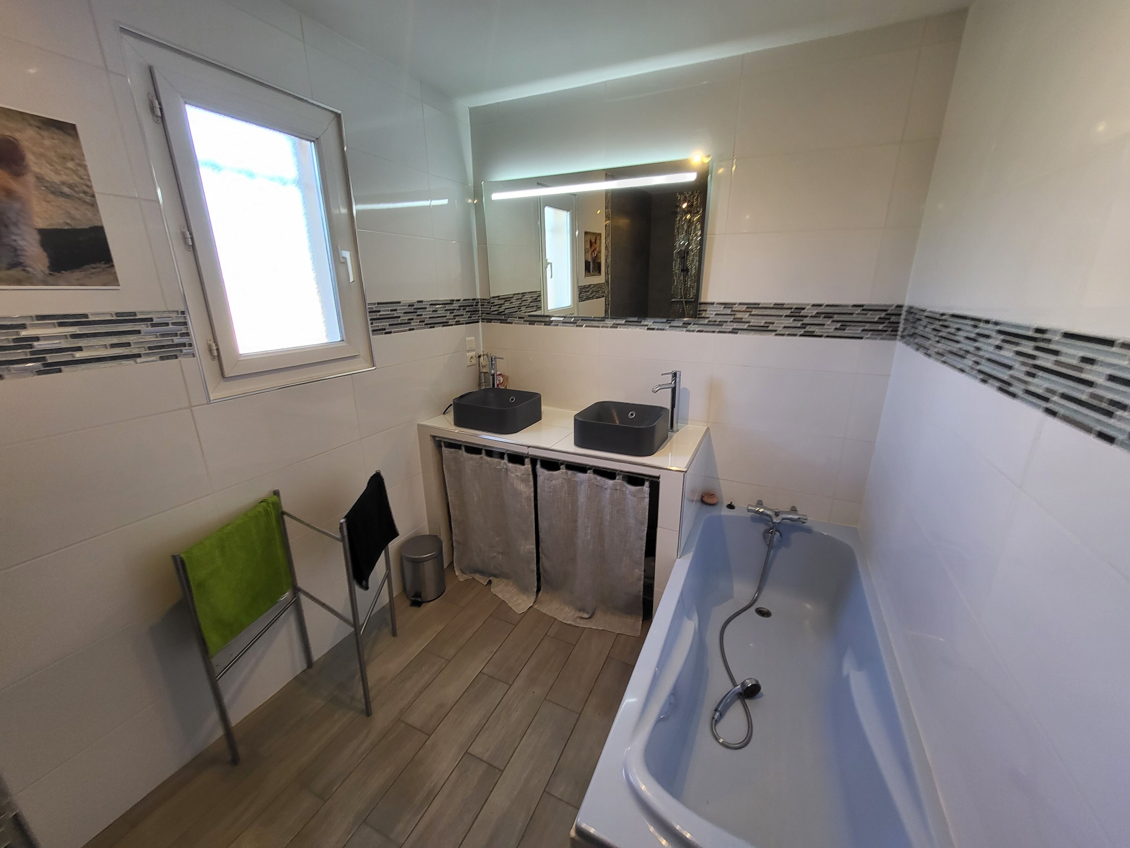 A bathroom with a bathtub, two sinks, a window, and a mirror.