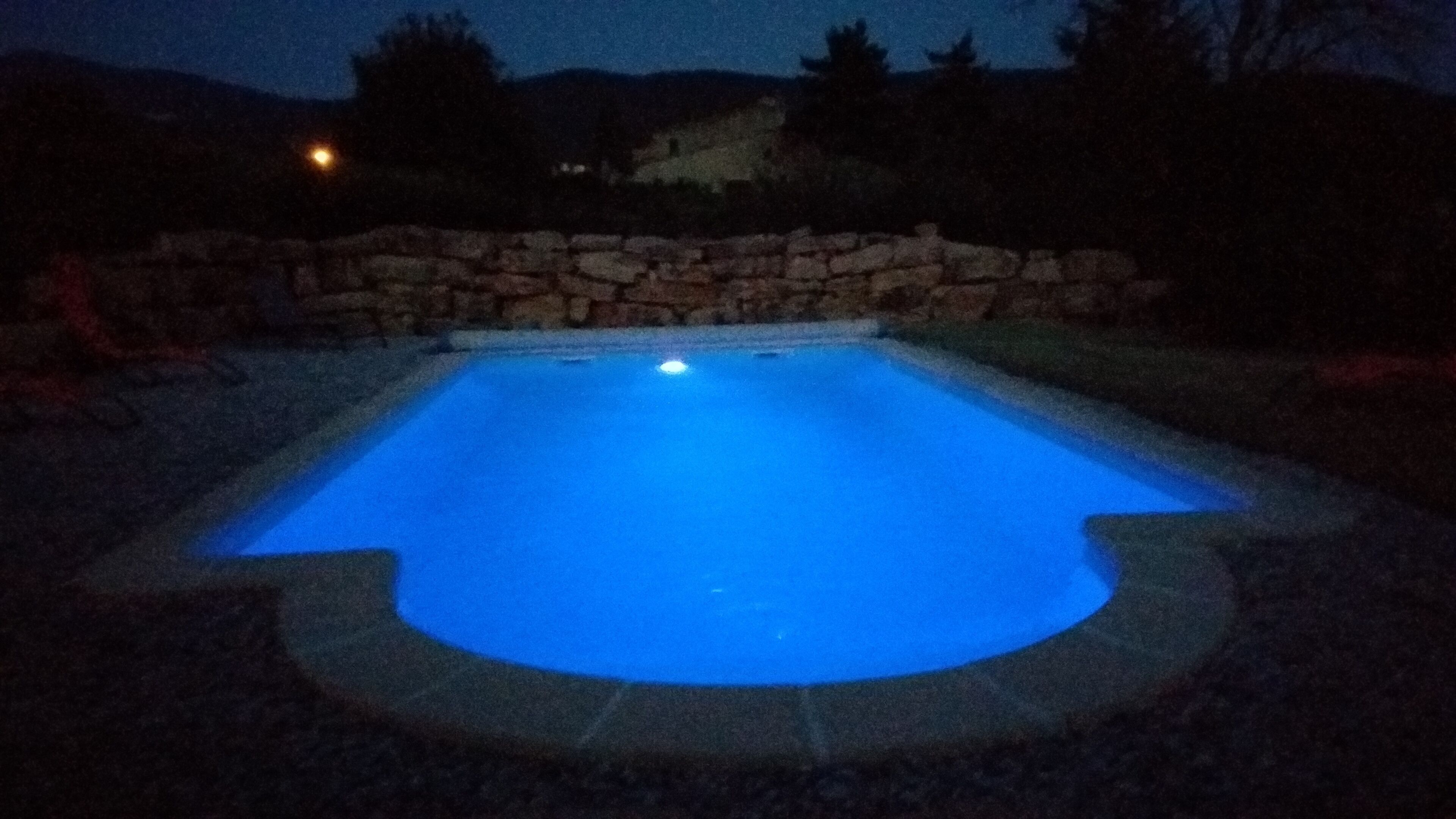 Une piscine entourée d’un mur en pierre.