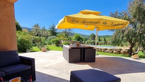 An outdoor patio area with wicker furniture, a yellow umbrella, and a stone wall. - Villa at the foot of Mont Ventoux for 7 people in Malaucène with private pool (Malaucène)