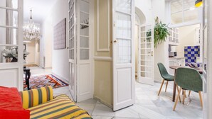 A spacious living area with a red sofa, a patterned rug, and a chandelier. - Families, calm city center 3 bedrooms 5 bathrooms wifi air conditioning heating (Sevilla)