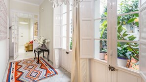 A hallway with a patterned rug, a chandelier, and potted plants by a large window. - Families, calm city center 3 bedrooms 5 bathrooms wifi air conditioning heating (Sevilla)