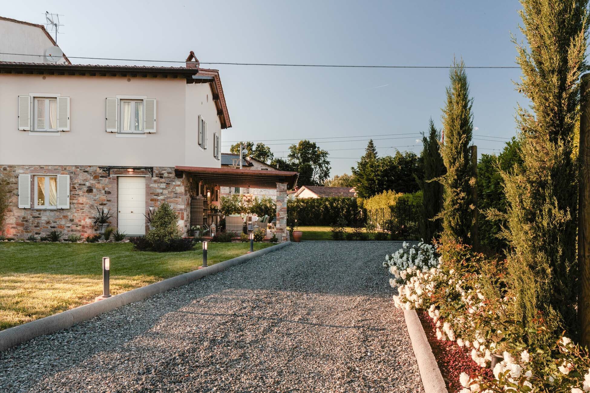 A two-story house with a stone facade, a front porch, and a gravel driveway leading to a white garage door.