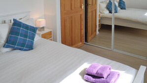 A bedroom with a bed, a nightstand, a wooden wardrobe, and a mirror. - 3 bedroom accommodation in St. Just (St. Just)