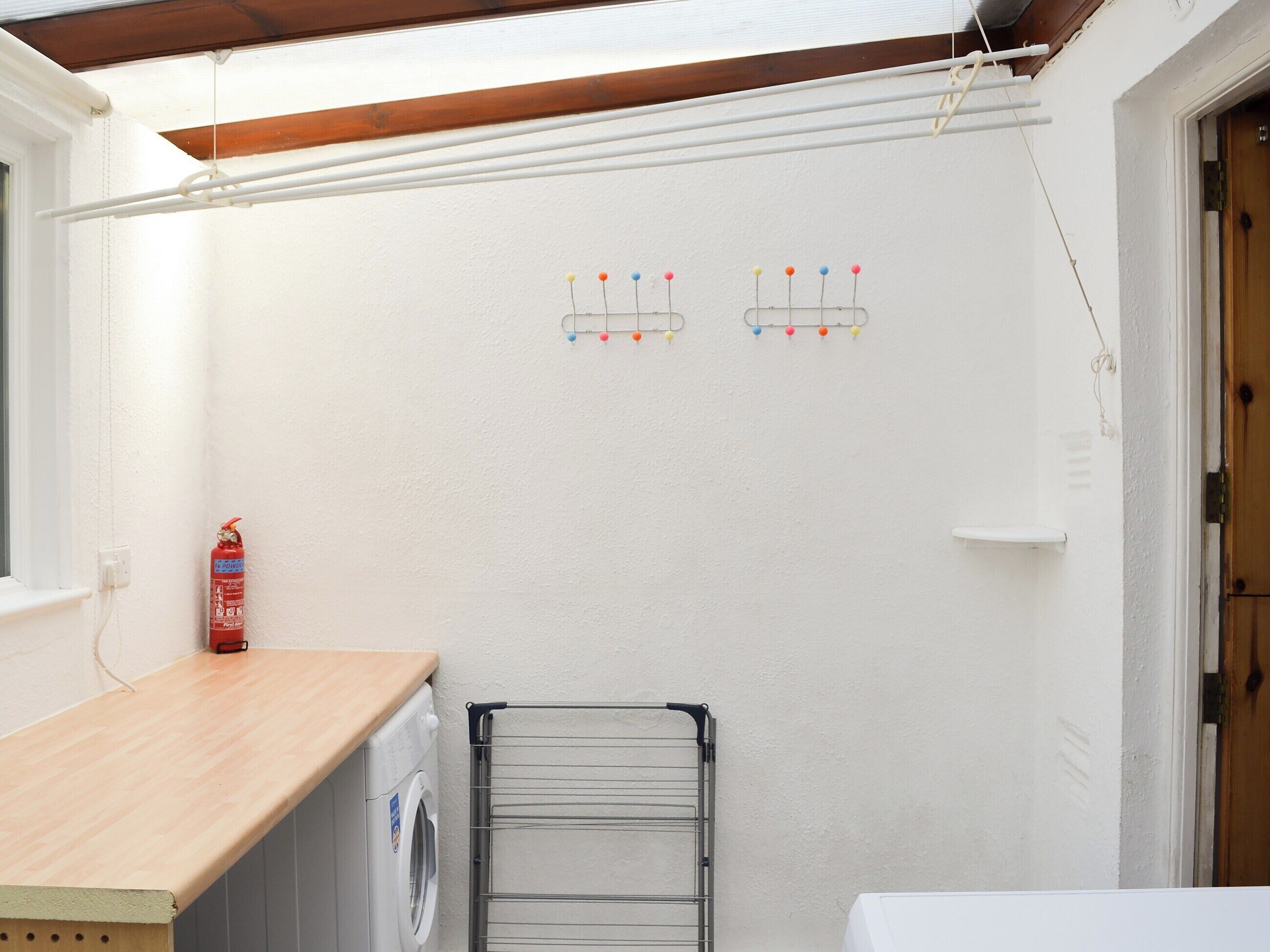 A laundry area with a washing machine, a drying rack, and a fire extinguisher.