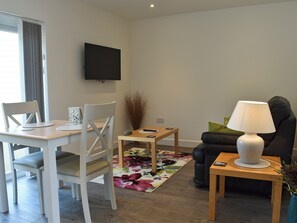 Un salon comprenant une table à manger, des chaises, un canapé, un téléviseur, une lampe et un tapis à motifs floraux.