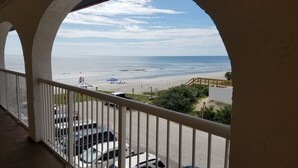 A balcony with a view of a beach, a parking area, and a lifeguard tower. - Ocean and Pool View Condo – Point East Condominium (New Smyrna Beach)