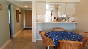 A dining area with a round table, wicker chairs, and a blue tablecloth. - Ocean and Pool View Condo – Point East Condominium (New Smyrna Beach)