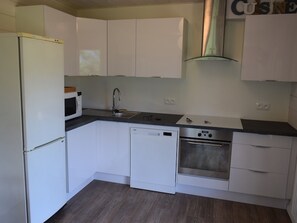 A compact kitchen with white cabinets, a microwave, a sink, a dishwasher, and an oven.