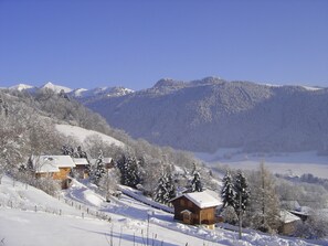A snow-covered mountain village with wooden houses and a clear blue sky.