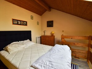 Ein Schlafzimmer mit Bett, Holz-Kopfteil, einem Schminktisch, einem Nachttisch und Wandbildern.