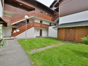 Un immeuble à plusieurs étages, doté d’une façade en bois et d’un espace extérieur couvert avec un escalier.