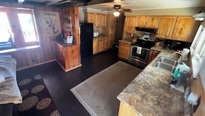 A kitchen with wooden cabinets, a refrigerator, a stove, and a sink. - Amazing view of Lake Norfork, room for everyone! (Mountain Home)