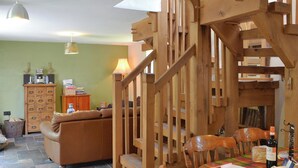 Una scala in legno conduce a una zona pranzo con un tavolo apparecchiato per due, un divano e un armadio con cassetti.